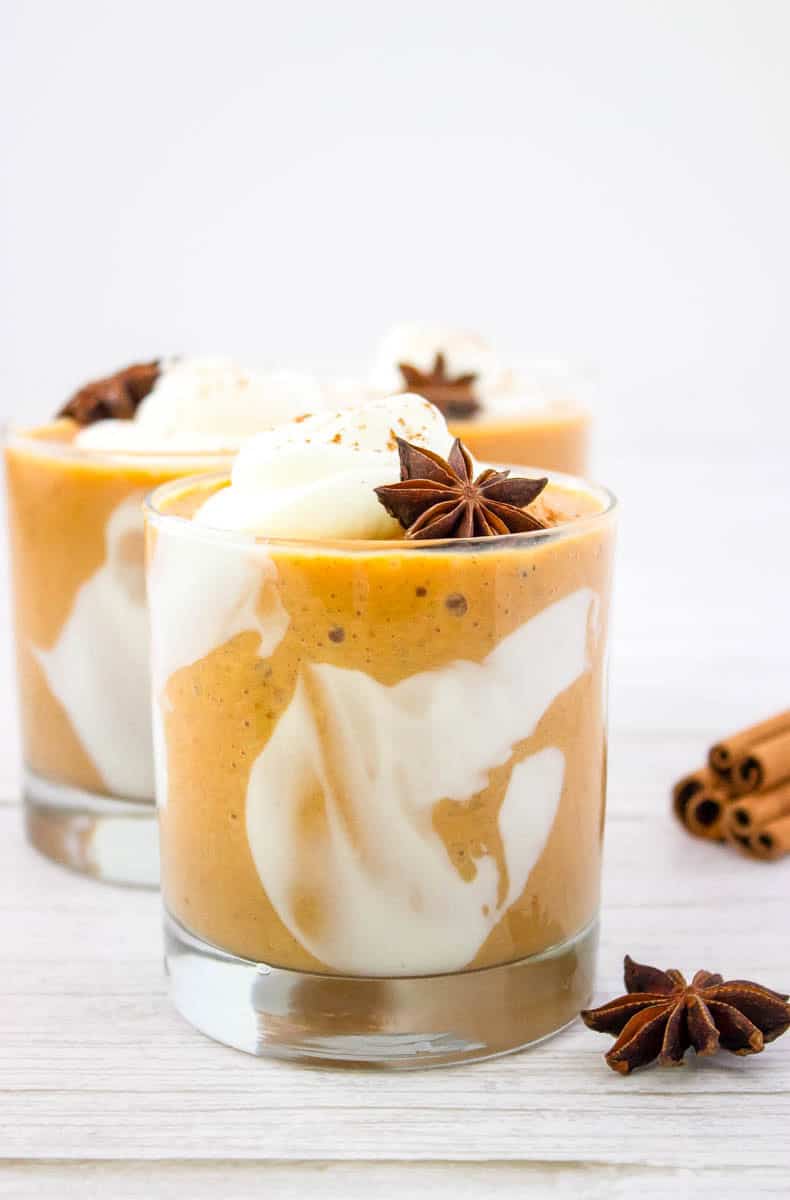 Three glasses of the pumpkin pie smoothie with sticks of cinnamon in the background.