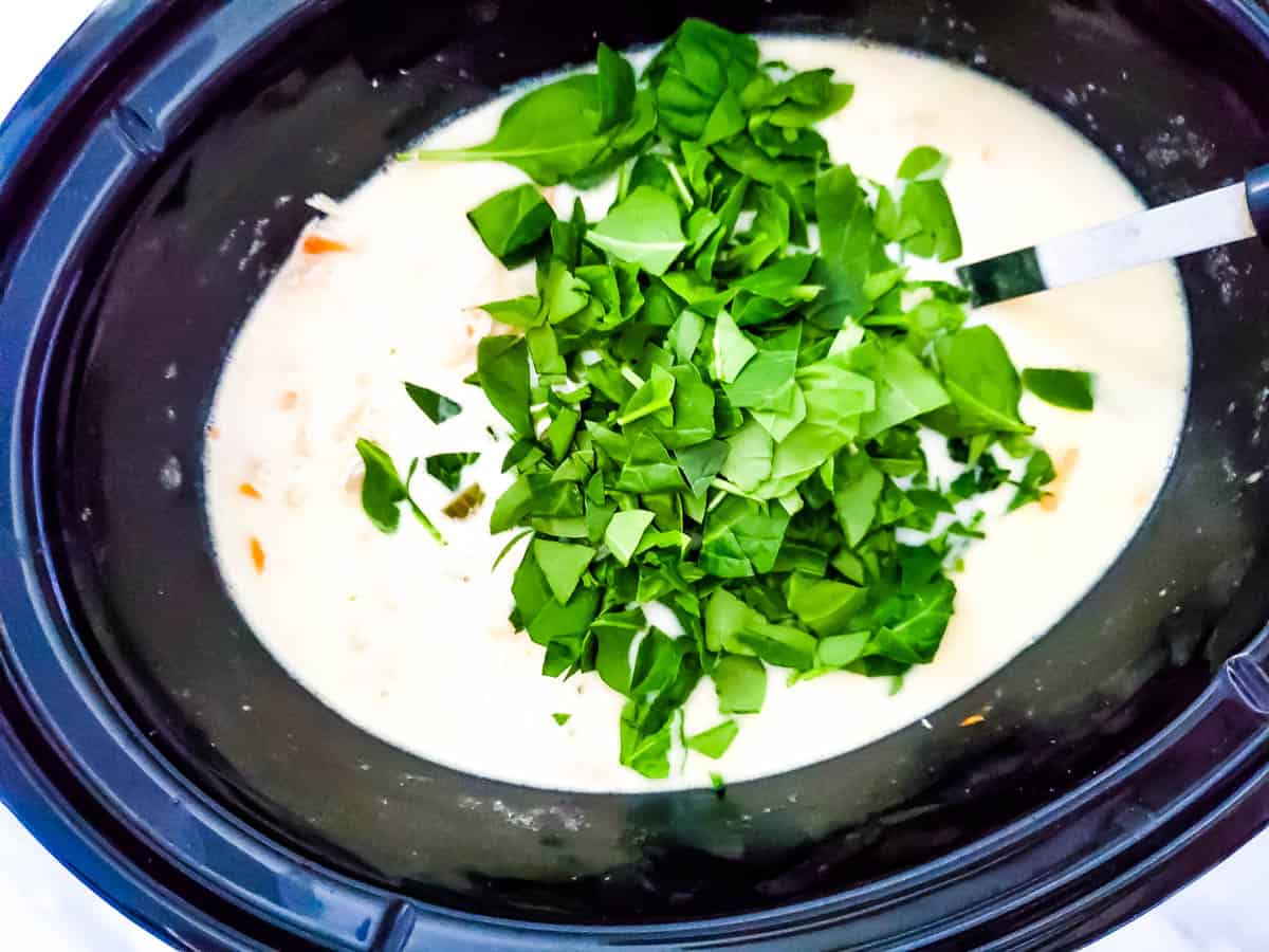 Spinach on top of the chicken mixture in the slow cooker.