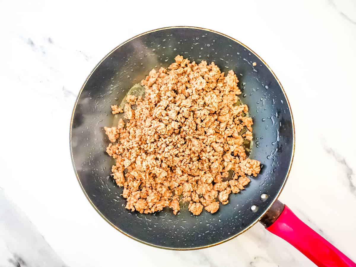 Skillet with browned turkey meat on white backdrop.