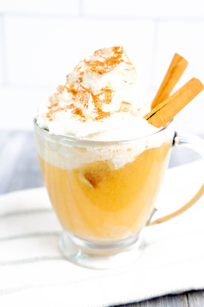 Apple Cider Float in a clear glass on a white towel with gray stripes on a gray/white background.