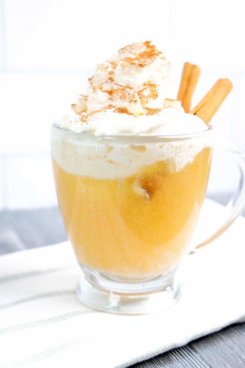 Apple Cider Float in clear glass on white towel with gray stripes with gray/white background.
