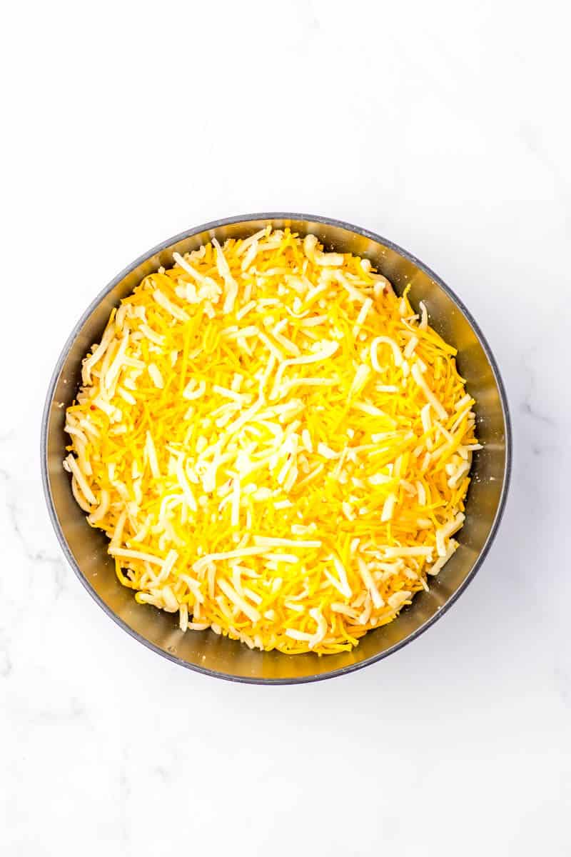 A medium size bowl with cheddar and pepper jack cheeses combined.