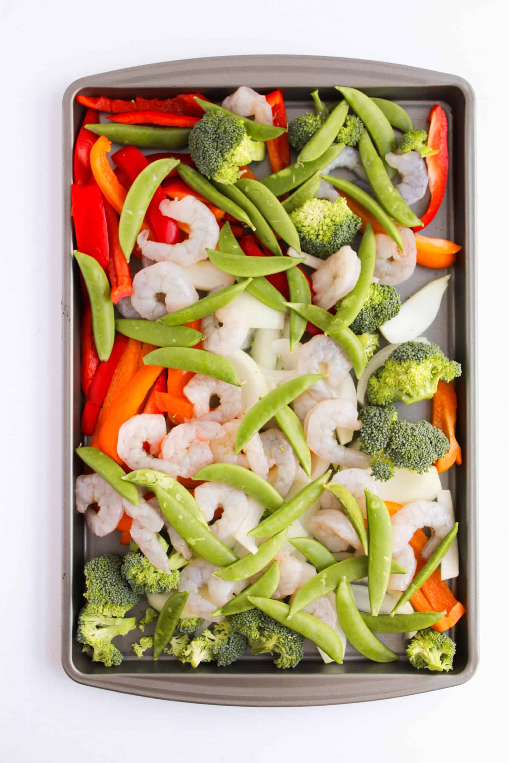 Sheet pan with chopped peppers, onions, broccoli florets and shrimp