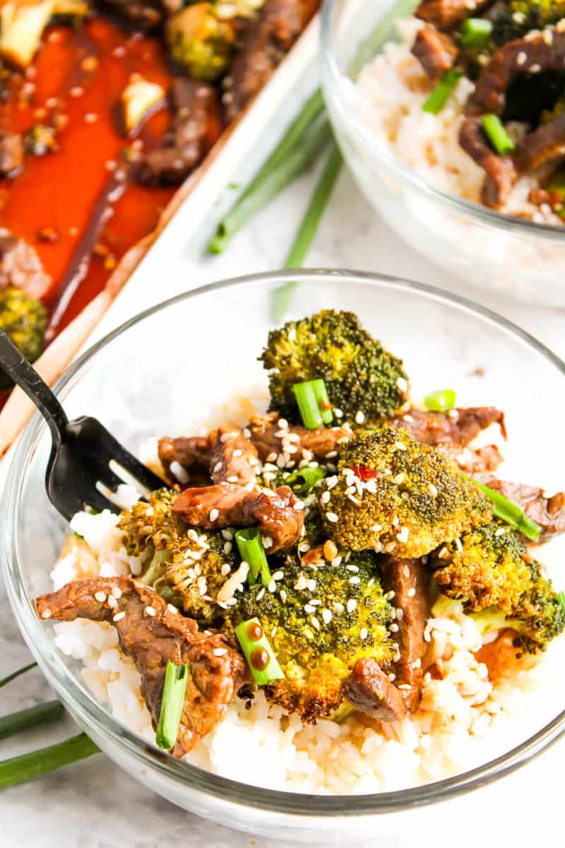 Clean bowl with beef and broccoli overtop rice with sheet pan in the background.