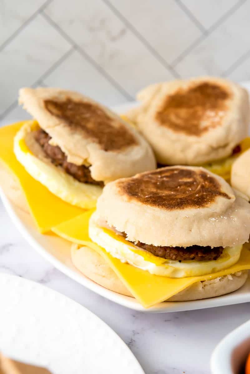 Plate of four breakfast sandwiches on white background.