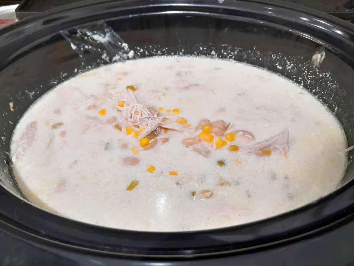 Crockpot white chicken chili after cream cheese has melted and everything is mixed together.
