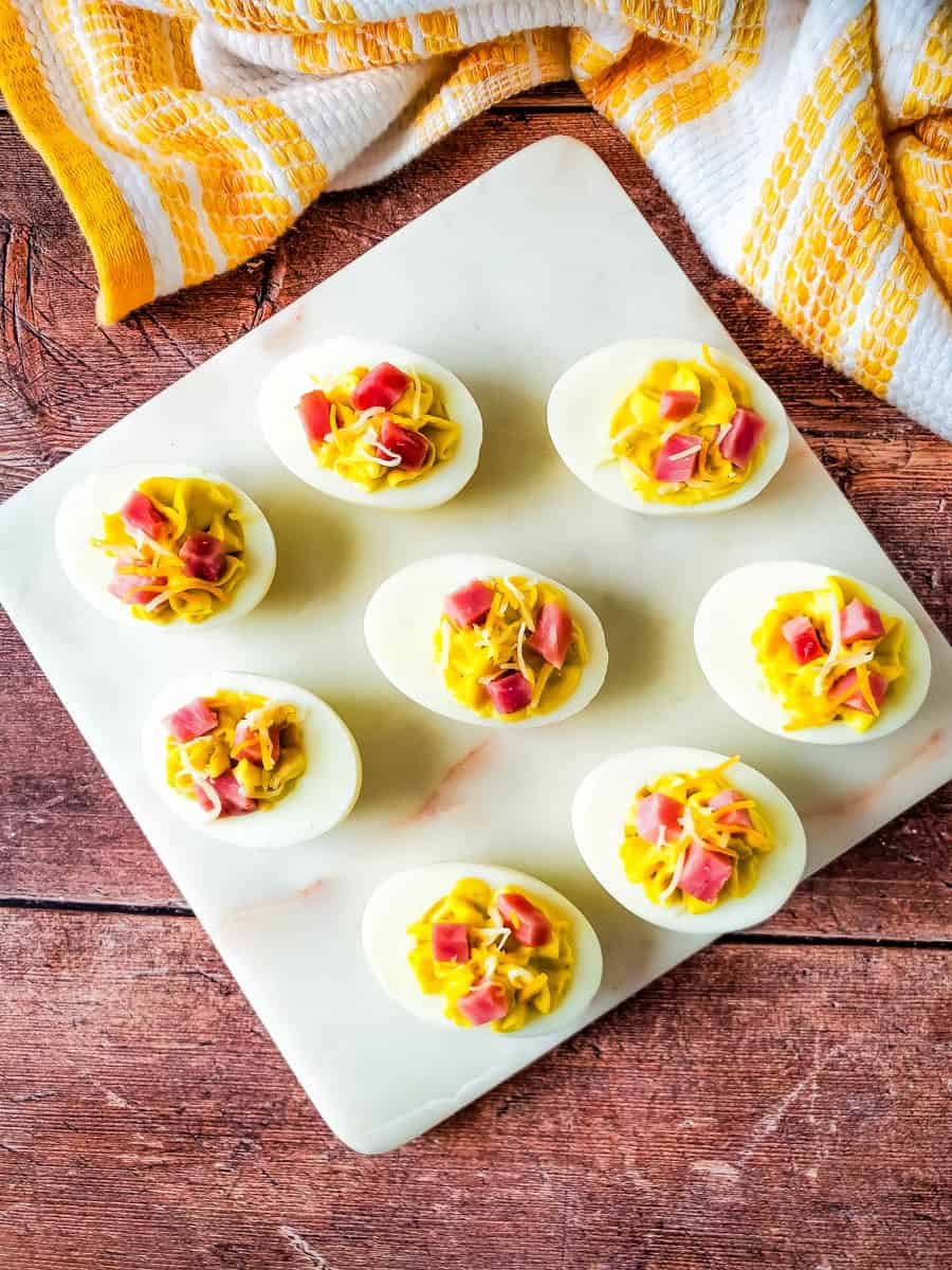 Ham and cheese deviled eggs on white plate