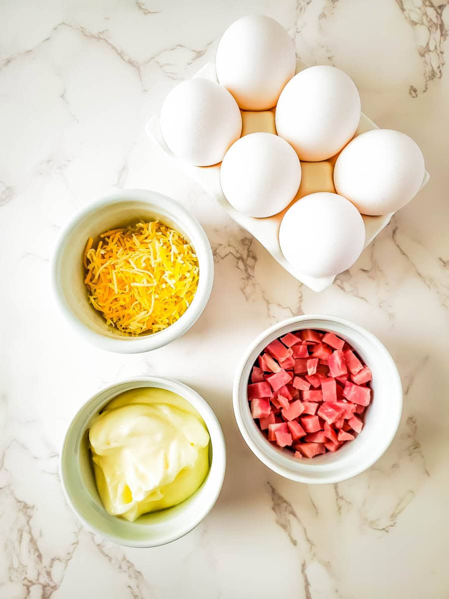 Ingredients for ham and cheese deviled eggs on marble background