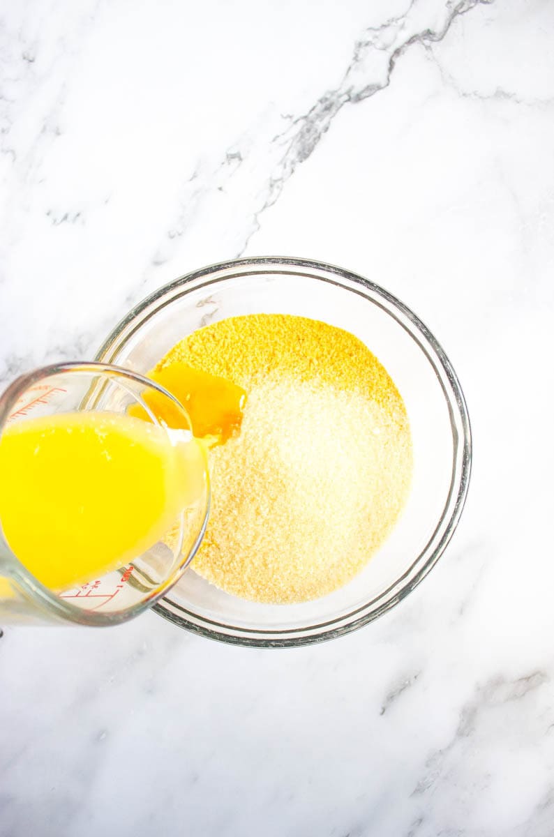 Egg yolks being poured into glass bowl with sugar, graham cracker crumbs.