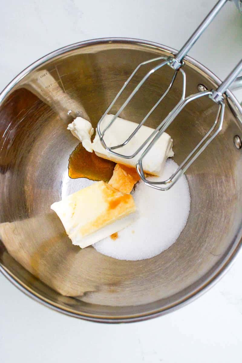 Cream cheese, sugar and vanilla being mixed in a bowl to make the cream cheese filling.