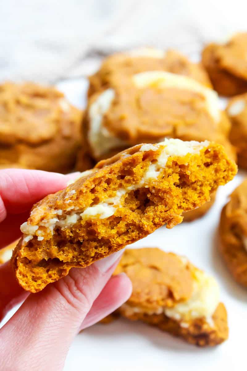 Close up of someone holding a cookie cut in half with remaining cookies in the background.
