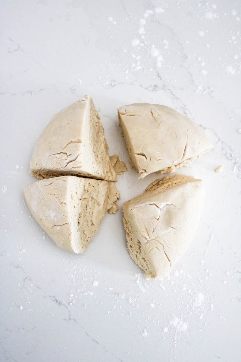 Dough cut into quarters to shape into the dinner rolls.