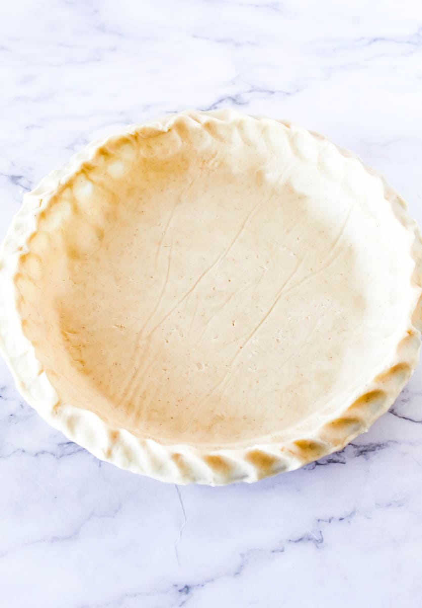 Pie crust fitted over a glass pie pan.