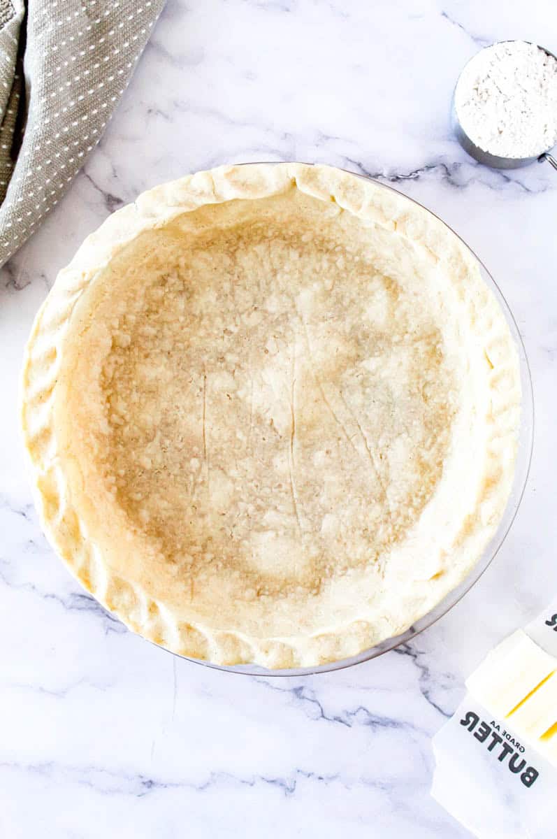 Gluten free pie crust in a glass pan on a marble top.