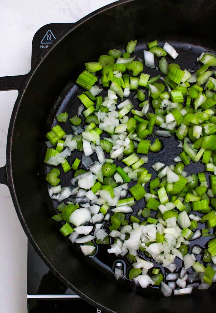 Celery, onions and garlic in a black cast iron pan