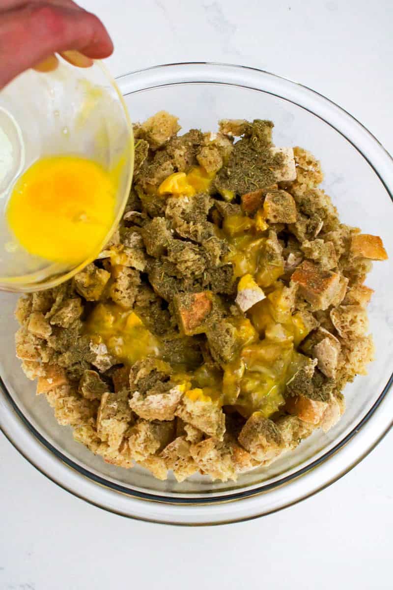 Eggs being poured into bowl with dried bread