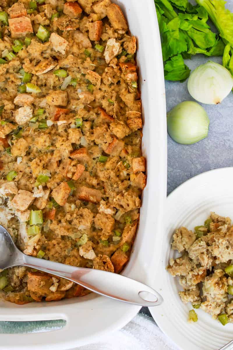 Casserole dish with gluten free thanksgiving stuffing and a metal spoon with plate next to dish with stuffing on it