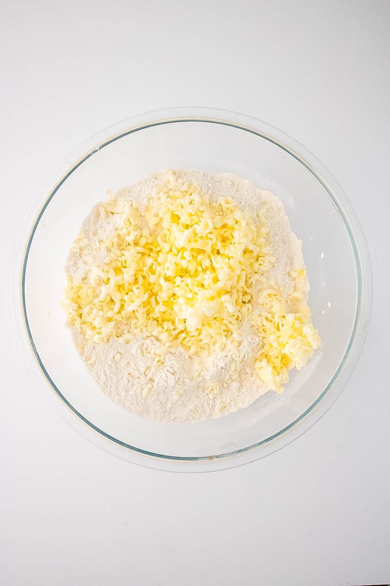 Grated butter with flour mixture in clear bowl.