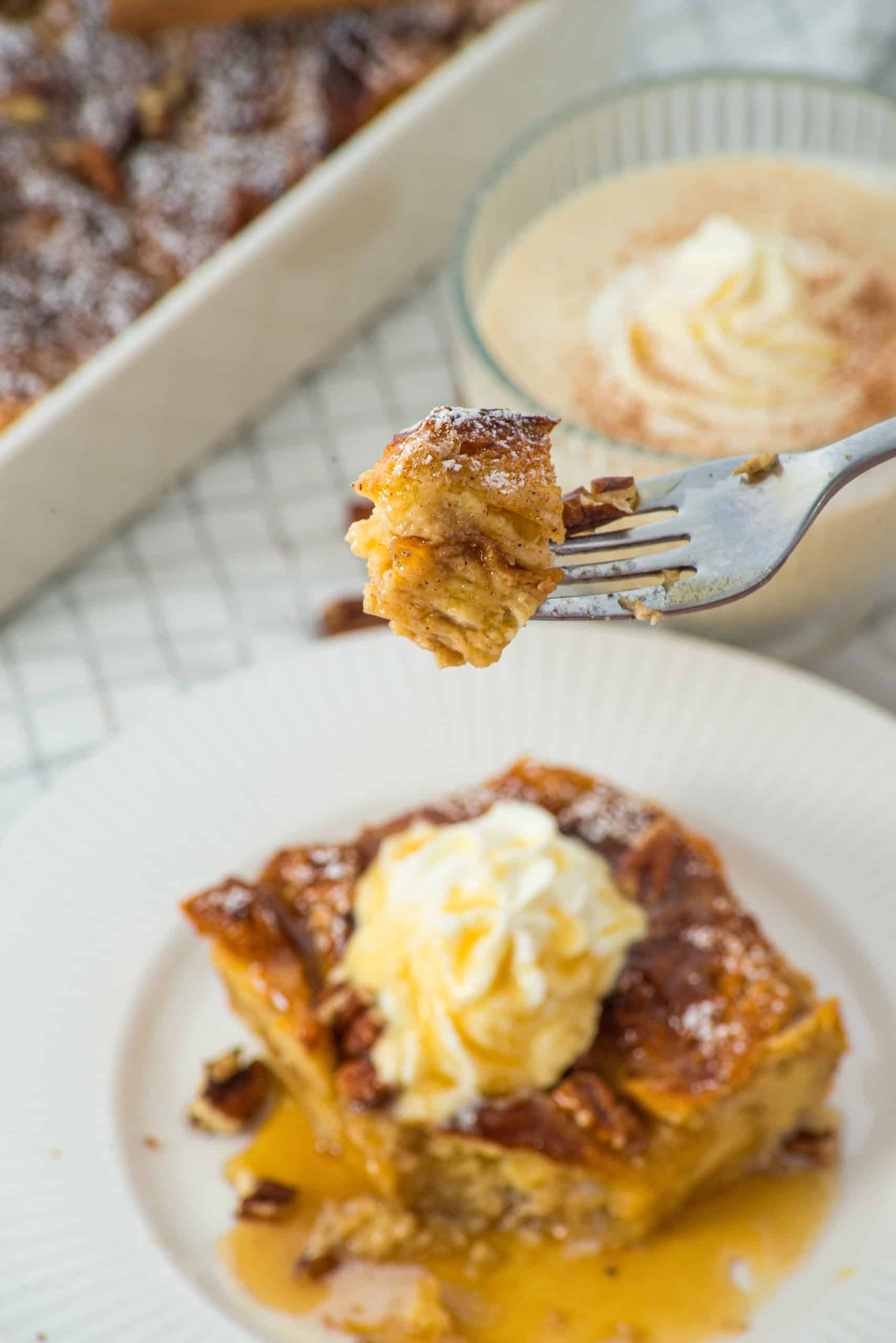 A piece of gluten free eggnog french toast on a plate with a fork lifting up a piece.