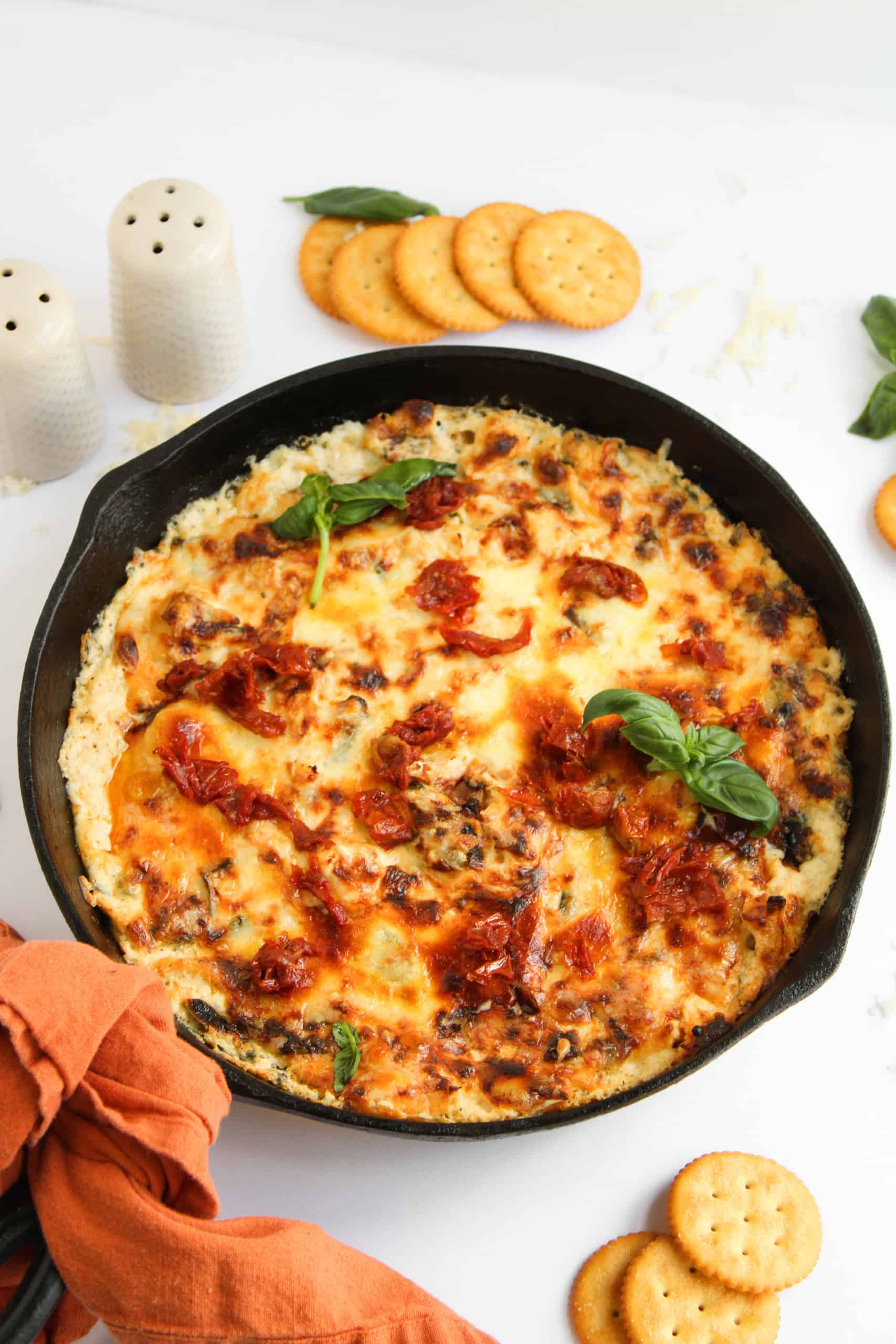 Skillet with Marry Me Chicken Dip on white with salt and pepper shakers along with crackers beside it.