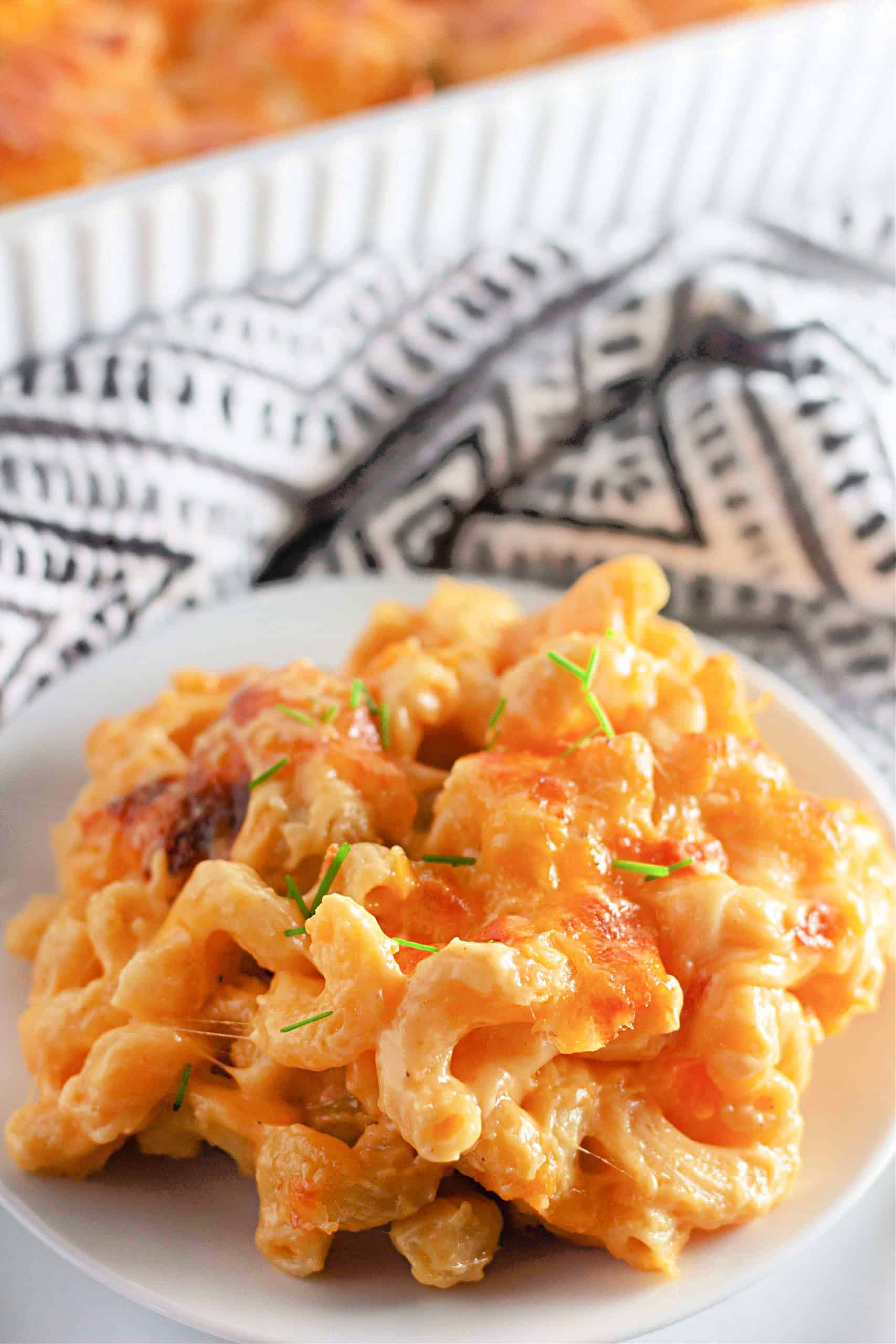 A plate of gluten free macaroni and cheese with black and white towel behind.