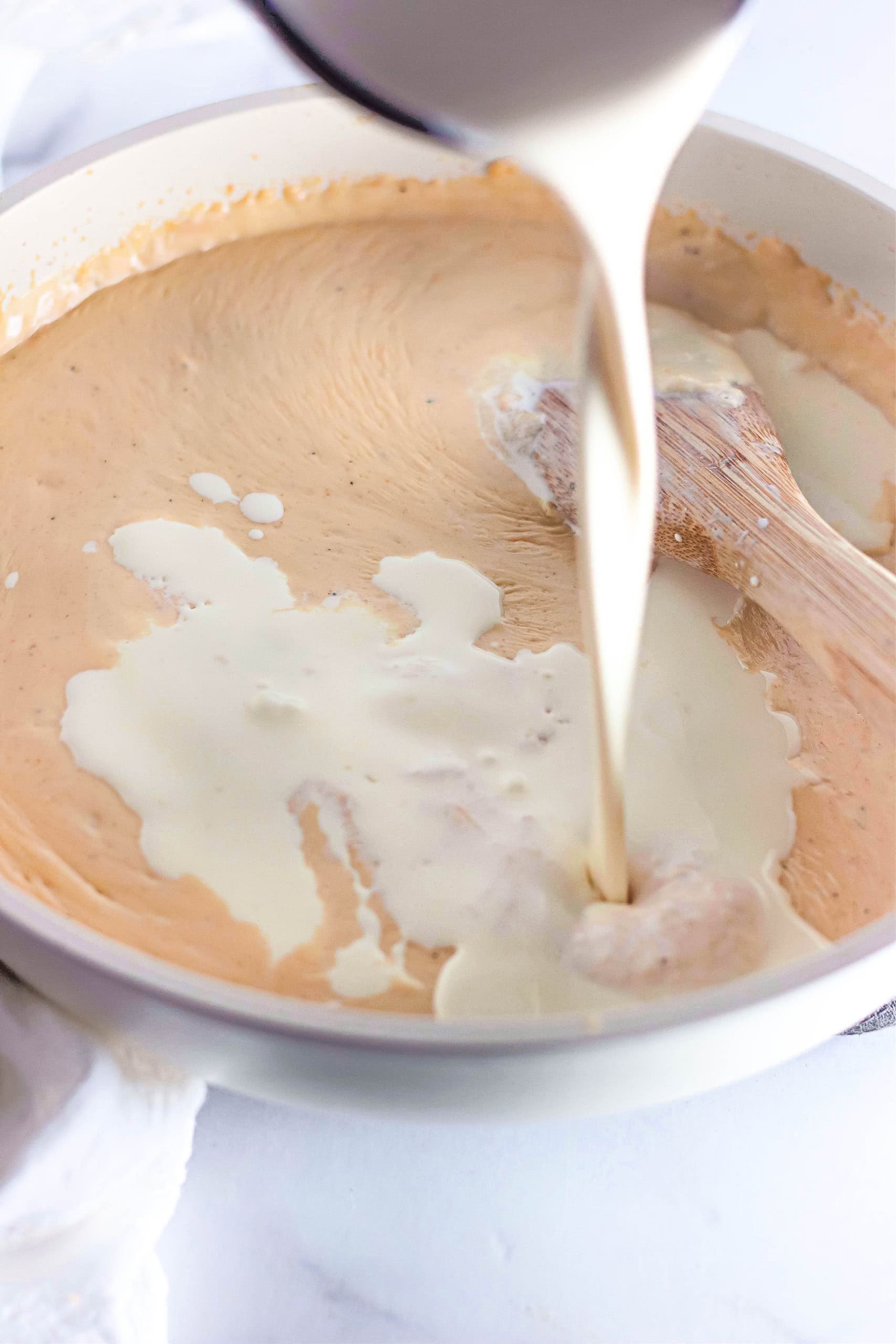 Heavy cream being poured in the roux.