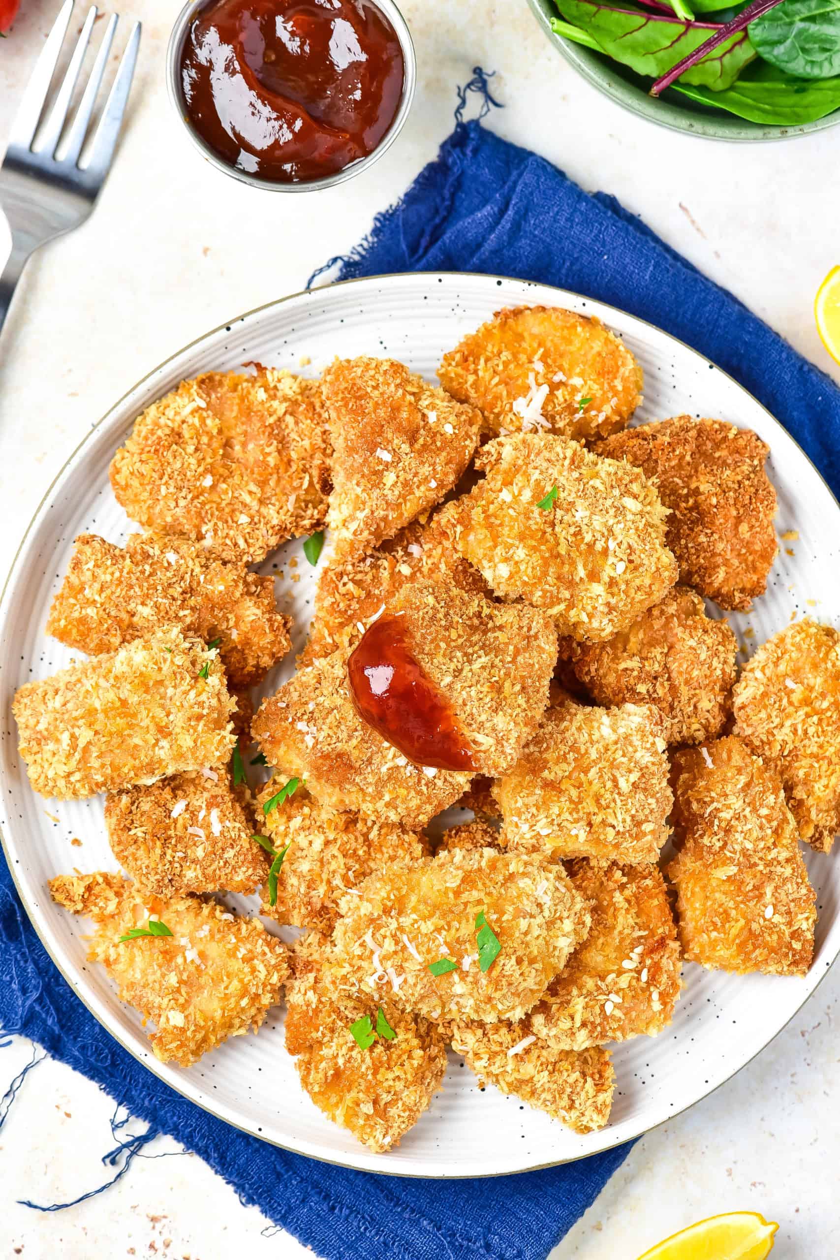 Plate of chicken nuggets on white plate with one nugget with ketchup