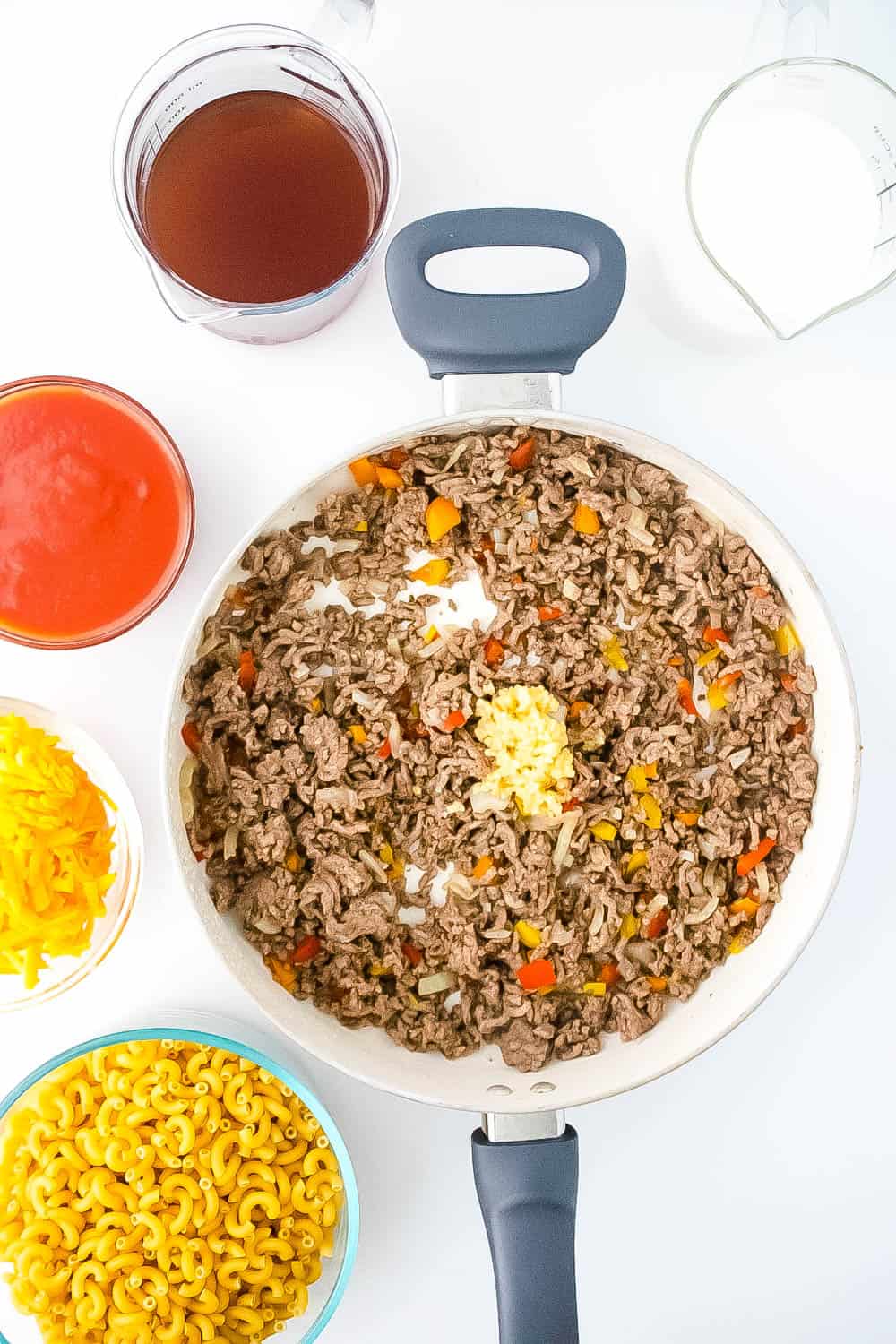 A skillet pan with ground, beef, onions, peppers and minced garlic cooking