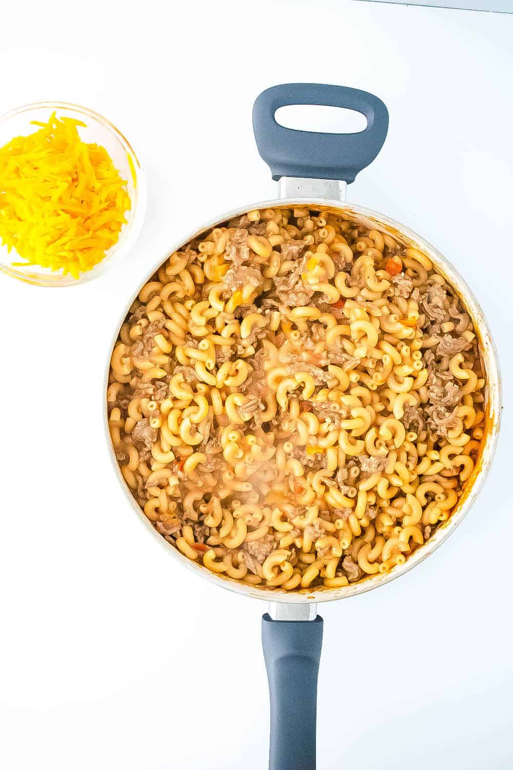 The noodles added to the meat mixture in the large skillet.