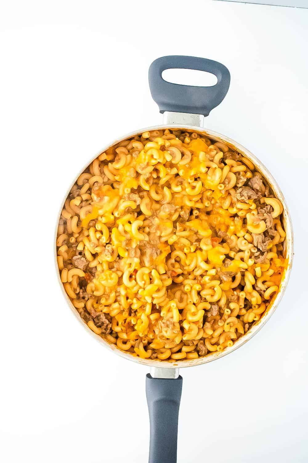 Melted cheese over the pasta and meat mixture in the large skillet.