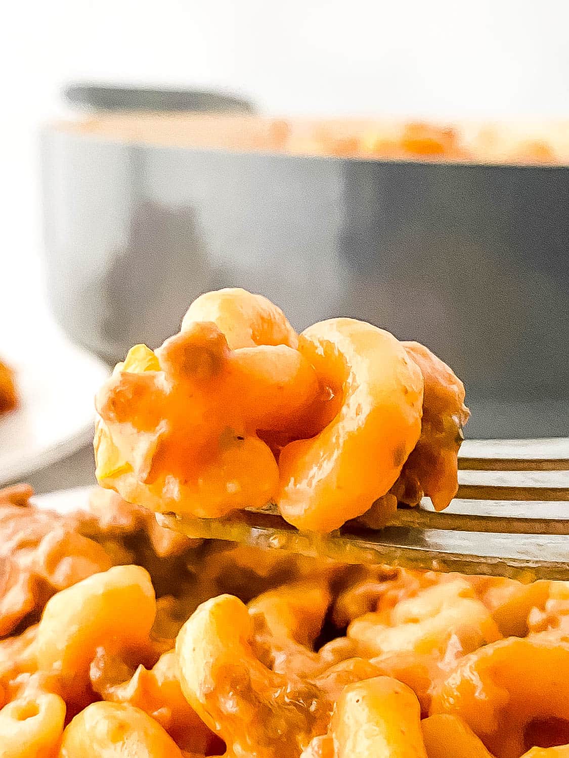 A close up shot of the hamburger helper on a fork being lifted into the air