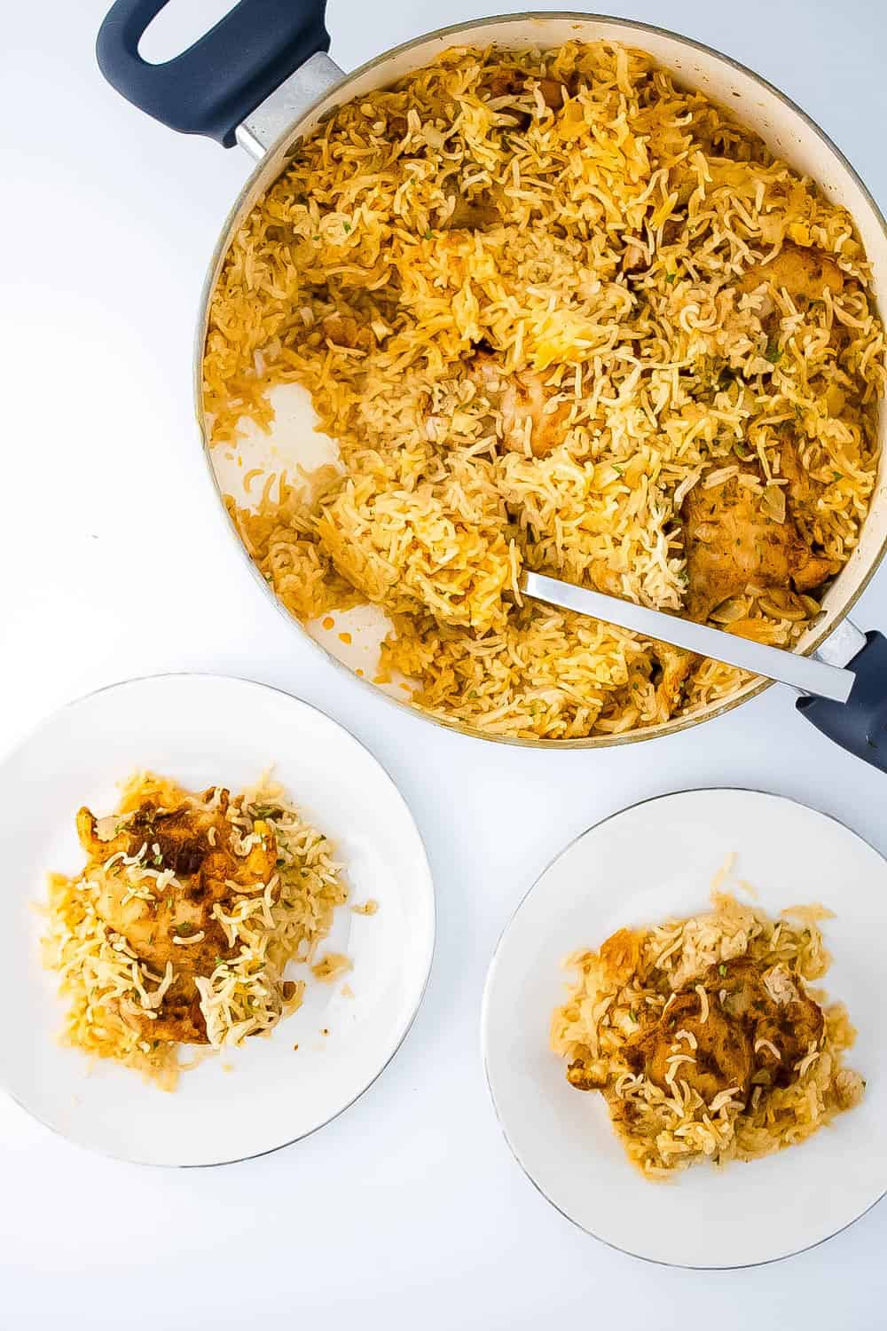 Two plate with chicken and rice on them next to the skillet