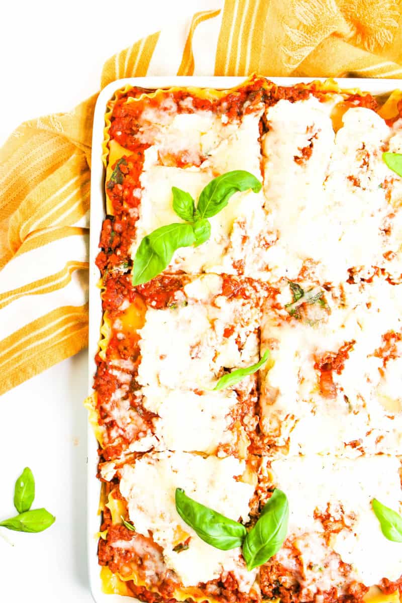 A sheet pan of gluten free lasagna with a yellow and white towel