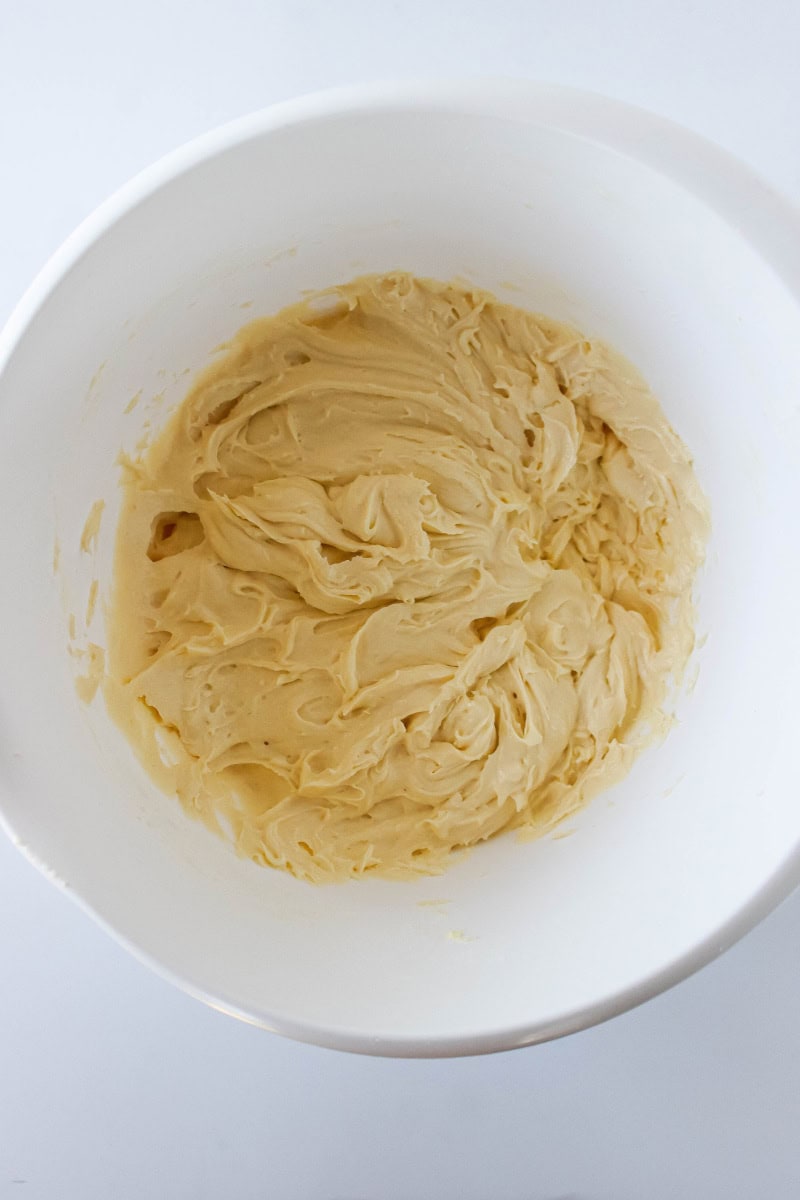 White bowl with flour, baking powder, salt, vanilla, eggs and butter combined together.