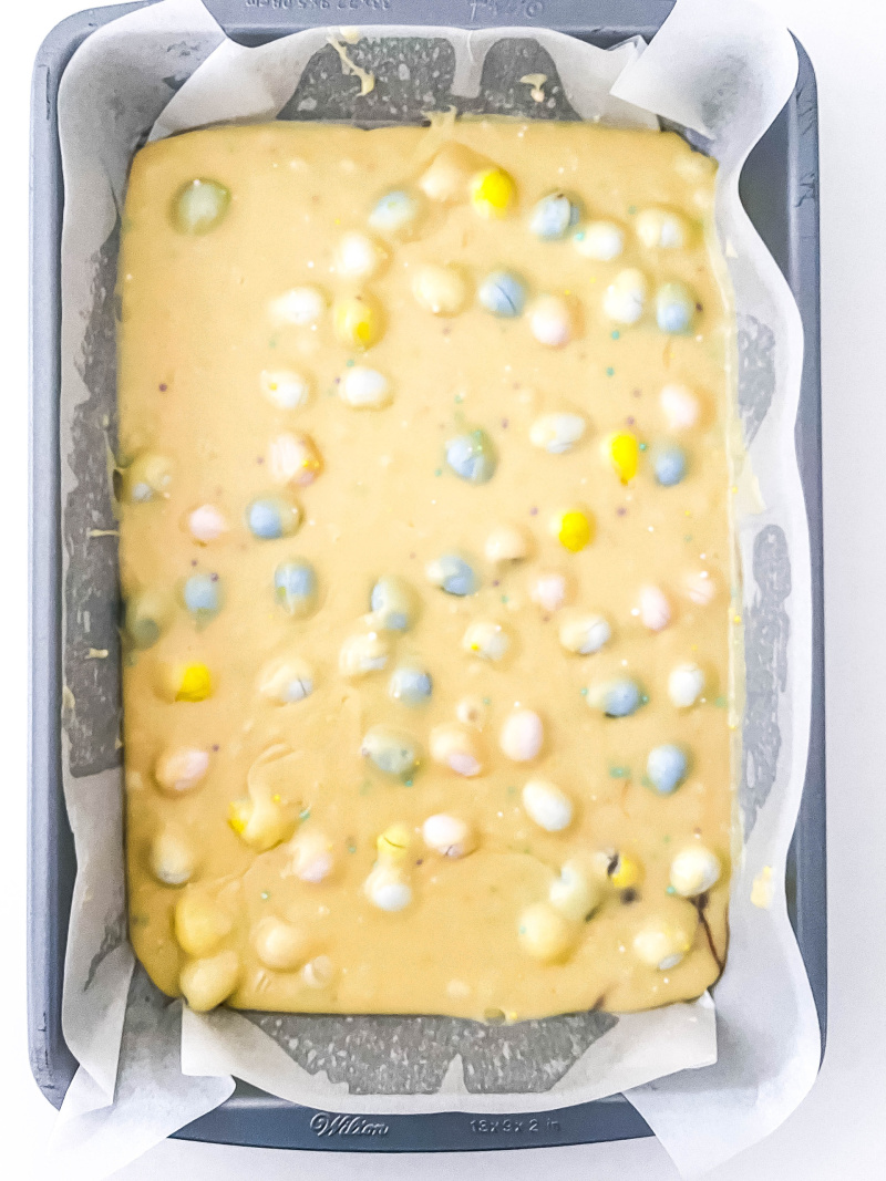 The white chocolate fudge mixture in pan with mini egg chocolates on top.