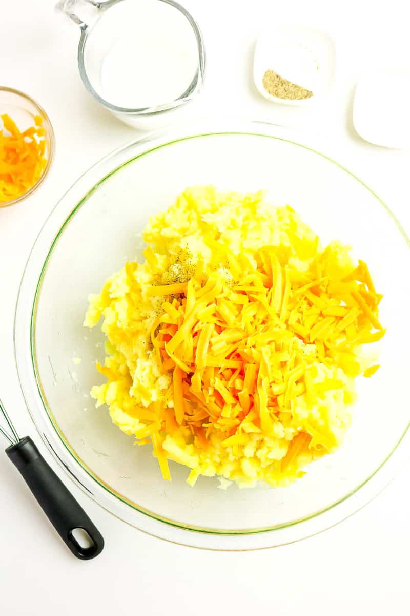 Shredded cheese being added to the mashed potatoes