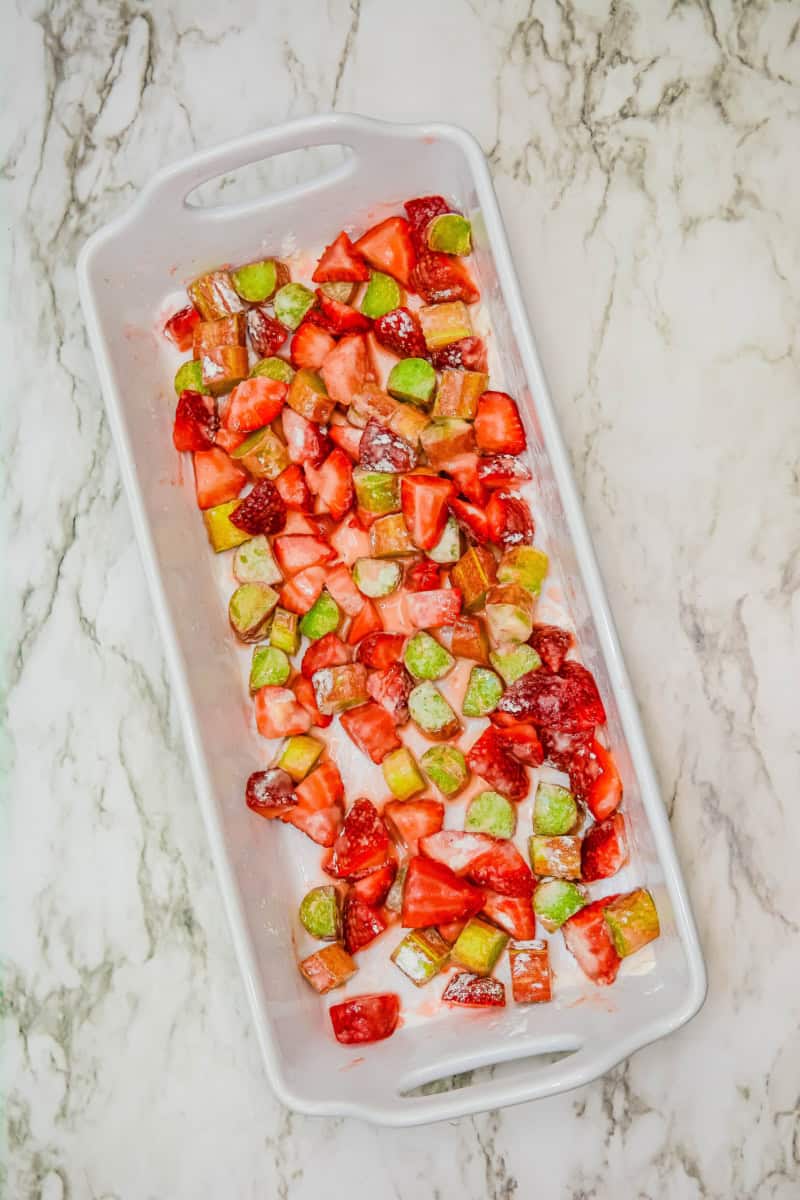 Chopped strawberries, rhubarb, lemon juice, sugar, cornstarch and salt in a white baking dish.