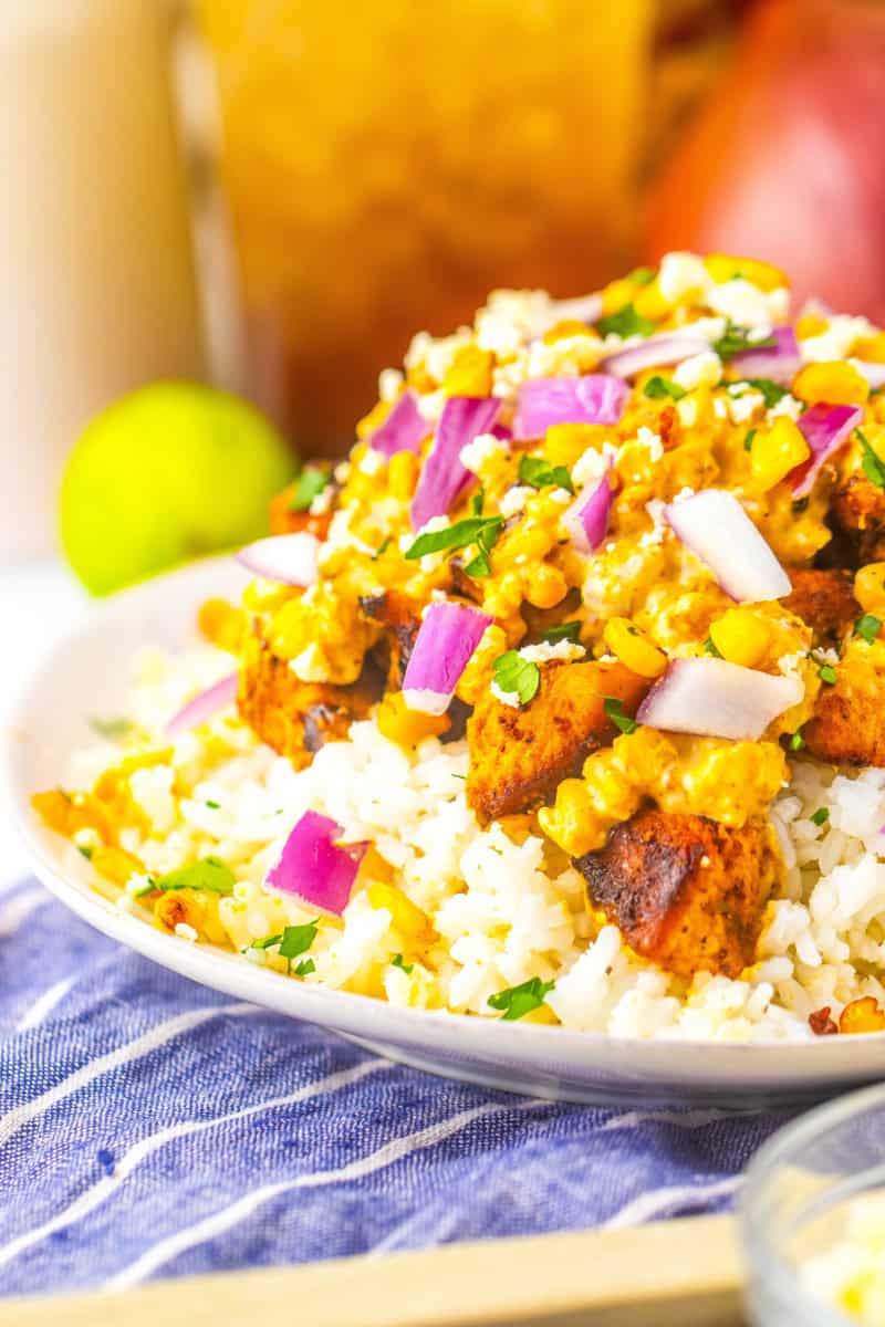 A bowl piled high with the Mexican street corn, chicken and rice.