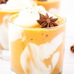 Close up shot a glass with pumpkin pie smoothie in with whipped cream and an allspice star for garnish.
