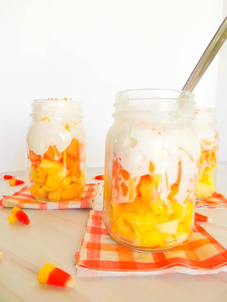 Candy corn parfait in three jars on orange checkered napkin