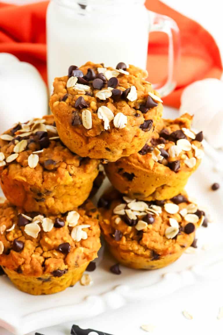 Pumpkin chocolate chip muffins stacked on a white background