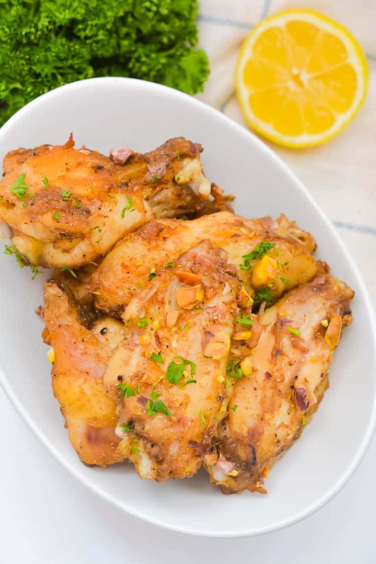 Baked Baklava Chicken Wings on white plate with lemon in background.