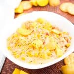 Bowl of sausage and potato soup in bowl on brown backdrop with crackers