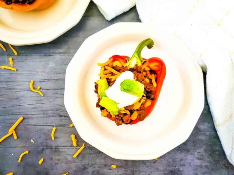 One stuffed taco pepper on a white plate on a dark background.
