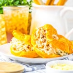 Marry Me Chicken Salad on croissant rolls on a white plate with ice tea in the background.