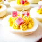 Close up of one ham and cheese deviled egg on white cutting board