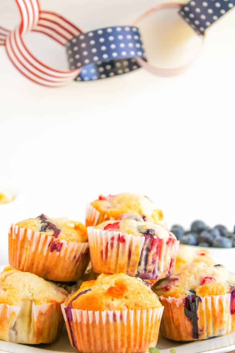 4th of July muffins stacked with cup of blueberries in back corner.