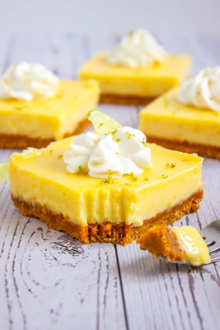 A close up shot of the key lime pie bar with a bite cut out by the fork next to the bar.