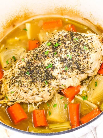 Turkey breast in dutch oven on top of vegetables.