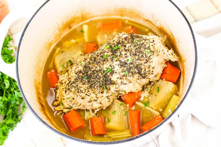 Turkey breast in dutch oven on top of vegetables.